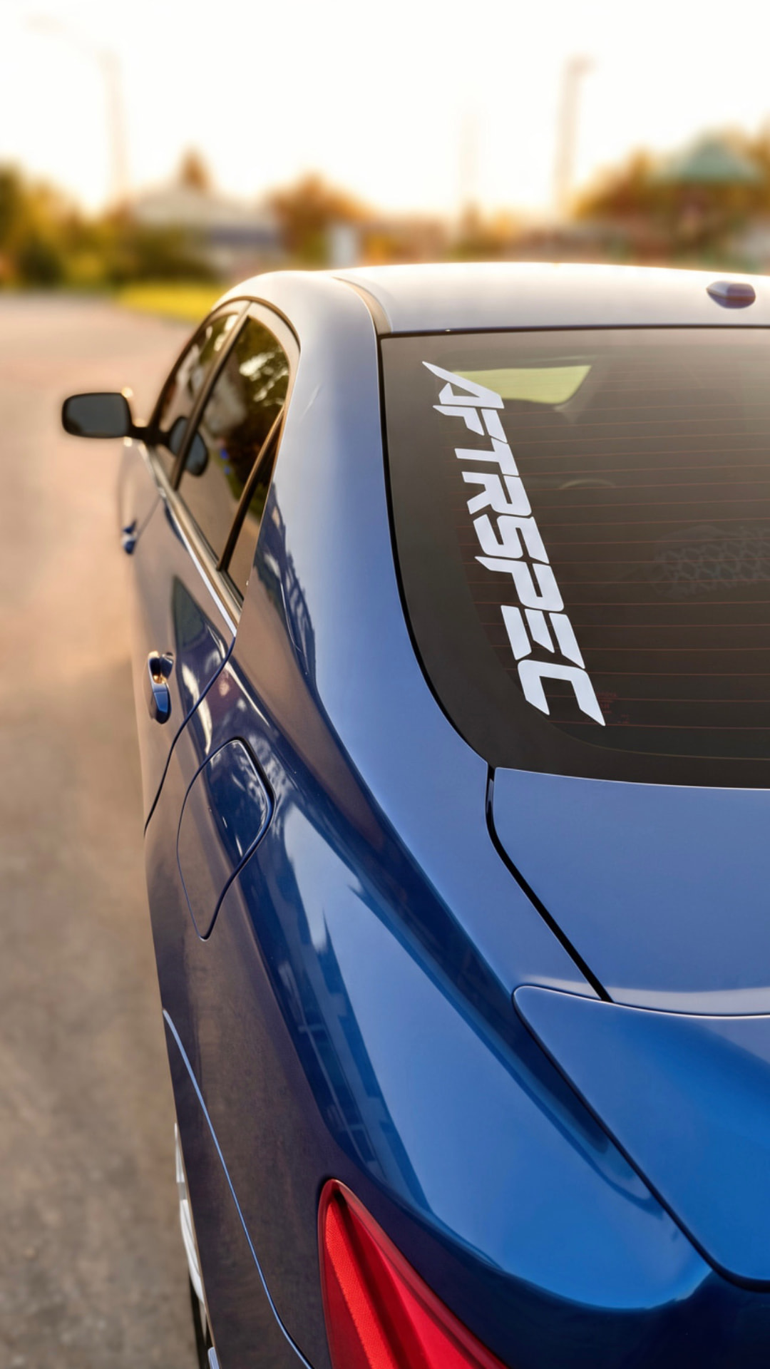 Blue coupe with AFTRSPEC rear-window banner at golden hour